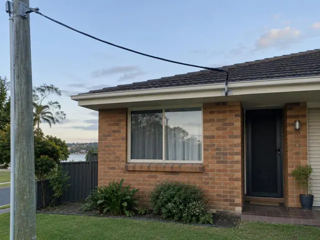 Brick house with overhead service cable and fascia bracket on the roof edge in Budgewoi